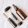 Flat lay of essential oil bottles and face roller on a textured white background.