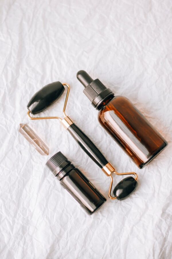 Flat lay of essential oil bottles and face roller on a textured white background.