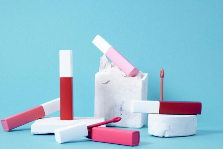 Colorful lip glosses arranged artistically against a blue backdrop showcasing vibrant hues.