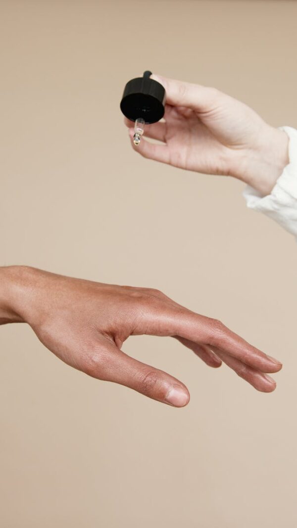 Two hands applying skin care oil with a dropper. Ideal for wellness and beauty themes.