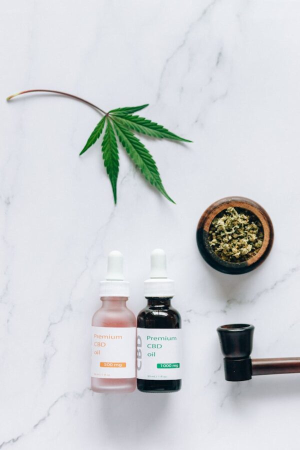 Flat lay of CBD oil bottles and hemp leaf, emphasizing natural wellness products.